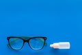 Eye drops in small bottle near glasses on blue background top view copy space Royalty Free Stock Photo