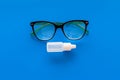 Eye drops in small bottle near glasses on blue background top view copy space Royalty Free Stock Photo