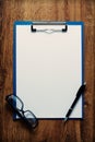 Eye-glasses and a black pen on an empty white page Royalty Free Stock Photo