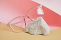 eye glasses on a concrete podium on a pink and beige background, trend composition, black stylish eye glasses,