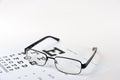 Eye glasses on eyesight test chart background