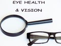 Eye health and vision note written on a white paper. A pair of black frame glasses and a magnifier. Royalty Free Stock Photo