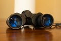 Eye level close up of black binoculars laying on a wood table Royalty Free Stock Photo