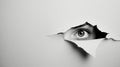 An eye looking through a torn hole in paper or wall. Royalty Free Stock Photo