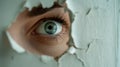 An eye looking through a torn hole in paper or wall. Royalty Free Stock Photo