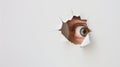 An eye looking through a torn hole in paper or wall. Royalty Free Stock Photo