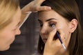 Eye makeup woman applying eyeshadow powder. Stylist is doing make up for female by eyeliner Royalty Free Stock Photo