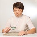 Woman with glasses and a magnifying glass reading a newspaper Royalty Free Stock Photo