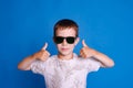eye protection from the sun. child boy in sunglasses show thumb up on light blue studio background Royalty Free Stock Photo