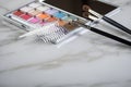 Eye shadow palette, brushes and artificial eyelid crease double tapes for eye makeup on marble beauty desk table Royalty Free Stock Photo