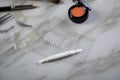 Eye shadow palette, brushes, fake lashes, tweezers and artificial eyelid crease double tapes for eye makeup on marble beauty desk Royalty Free Stock Photo