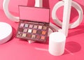Of an eye-shadow palette on a pink background featuring an array of shimmering eye-shadows