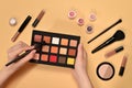 Eye shadow palette on woman hand. Professional makeup products with cosmetic beauty products, foundation, lipstick,  eye shadows, Royalty Free Stock Photo