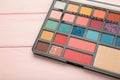 Eye shadows in different colors for fashionable professional trendy makeup. Shadow palette in pink background