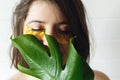 Eye Skin Care and Treatment. Portrait of beautiful young woman with natural makeup and golden eye patches at green monstera leaf. Royalty Free Stock Photo