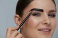 Eyebrow coloring. Woman applying brow tint with makeup brush Royalty Free Stock Photo