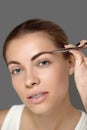 Eyebrow Correction. Beautiful young woman tweezing eyebrows. Model with beauty face Royalty Free Stock Photo