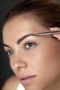 Eyebrow correction. Plucking eyebrows. Beautiful young woman with tweezers. Royalty Free Stock Photo