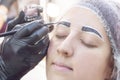 Eyebrow dyeing. beauty saloon. the girl lies with her eyes closed on the eyebrow dyeing procedure. The eyebrow master applies brus