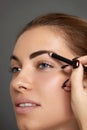 Eyebrow makeup. Beautiful model shaping brows with brow pencil closeup. Beauty woman with professional makeup contouring eyebrows. Royalty Free Stock Photo