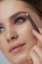 Eyebrow makeup. Beauty model shaping brows with brow pencil Royalty Free Stock Photo