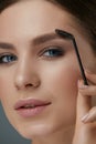 Eyebrow makeup. Woman brushing brows with gel brush closeup Royalty Free Stock Photo