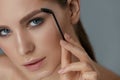 Eyebrow makeup. Woman brushing brows with gel brush closeup Royalty Free Stock Photo