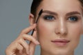 Eyebrow makeup. Woman brushing brows with gel brush closeup Royalty Free Stock Photo