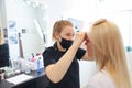 Eyebrow master stands in black clothes in front of the client and prepares for the dyeing procedure Royalty Free Stock Photo