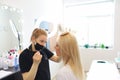 Eyebrow master stands in black clothes in front of the client and prepares for the dyeing procedure Royalty Free Stock Photo