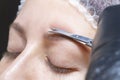 Eyebrow shaping in a beauty salon. the girl is trimmed with scissors for extra hair on her eyebrows. Royalty Free Stock Photo