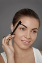 Eyebrows correction and contouring . Beautiful woman shaping brows with comb. Royalty Free Stock Photo