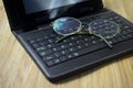 Eyeglass and laptop computer on wooden background