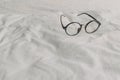 Eyeglasses with black plastic temple on white bed sheet Royalty Free Stock Photo