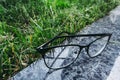 Eyeglasses in black rim liying on the granite surface near the grass