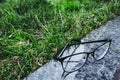 Eyeglasses in black rim liying on the granite surface near the grass