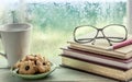 Eyeglasses on book with cookies and coffee cup on rainy day Royalty Free Stock Photo