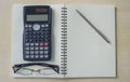 Eyeglasses,calculator and silver pen on spiral notebook