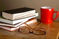 Eyeglasses, coffee mug and pile of books