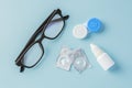 Eyeglasses and contact lenses with container on blue background Royalty Free Stock Photo