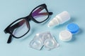 Eyeglasses and contact lenses with container on blue background Royalty Free Stock Photo