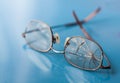 Eyeglasses with cracked lens on shiny blue background Royalty Free Stock Photo