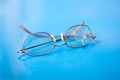 Eyeglasses with cracked lens on shiny blue background