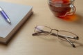 Eyeglasses, diary, blue pen and cup of tea on a brown table, selective focus Royalty Free Stock Photo