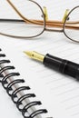 Eyeglasses and fountain pen on notebook Royalty Free Stock Photo