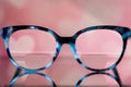 Eyeglasses Glasses with Bifocals and Black and blue Frame smudged view agaist a blurry pink background with white hearts. Blurry