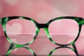 Eyeglasses Glasses with Bifocals and Black and green Frame smudged view agaist a blurry pink background with white hearts. Blurry