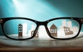 Eyeglasses lie on the open newspaper with paper houses