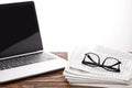 eyeglasses on newspapers and laptop with blank screen on wooden surface, on white Royalty Free Stock Photo