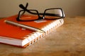 Eyeglasses, notebook and a pen